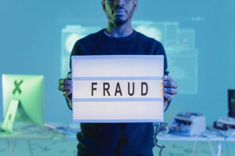 a man in black sweater holding letter board with fraud text